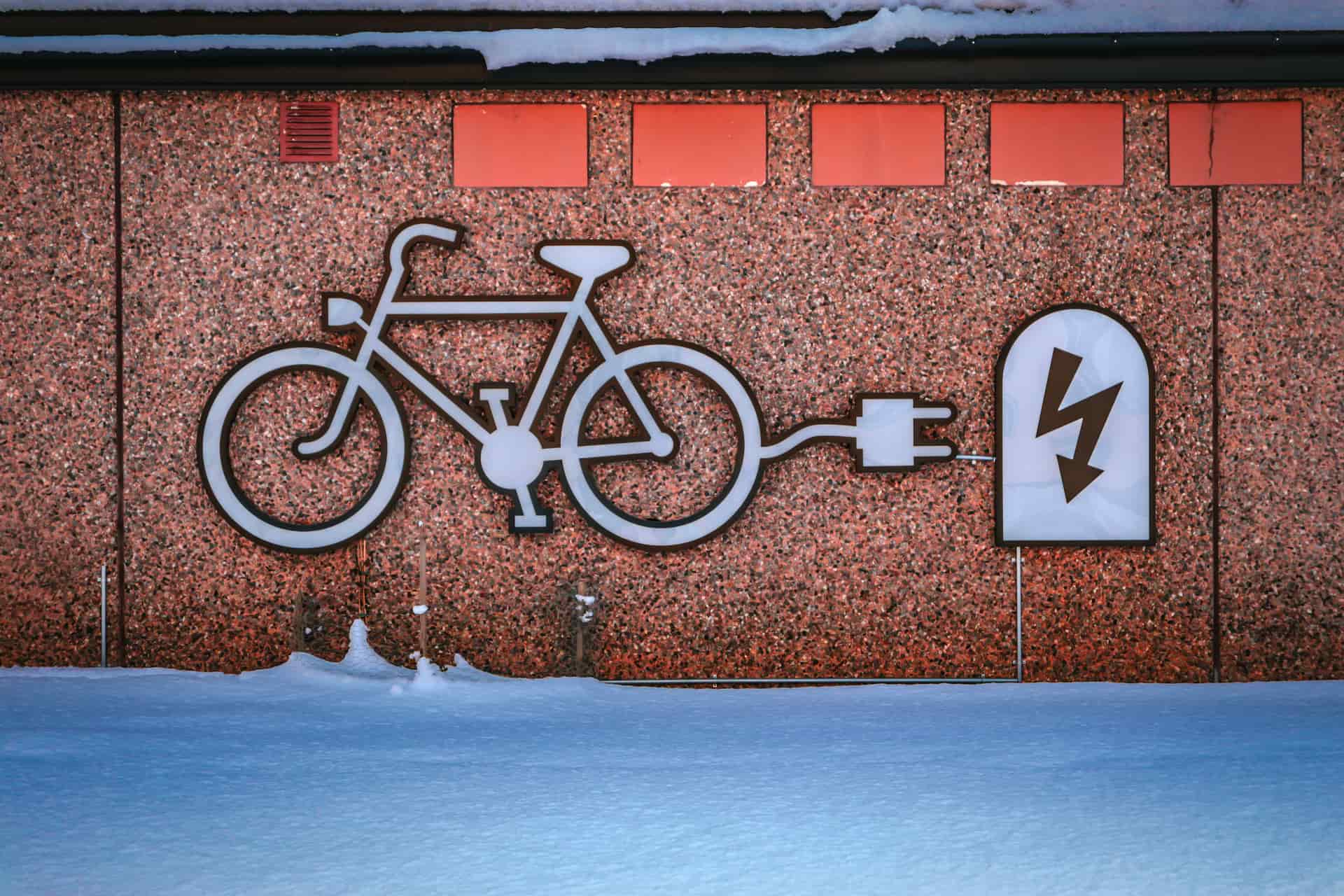 An electric bike charging from a wall outlet in a garage