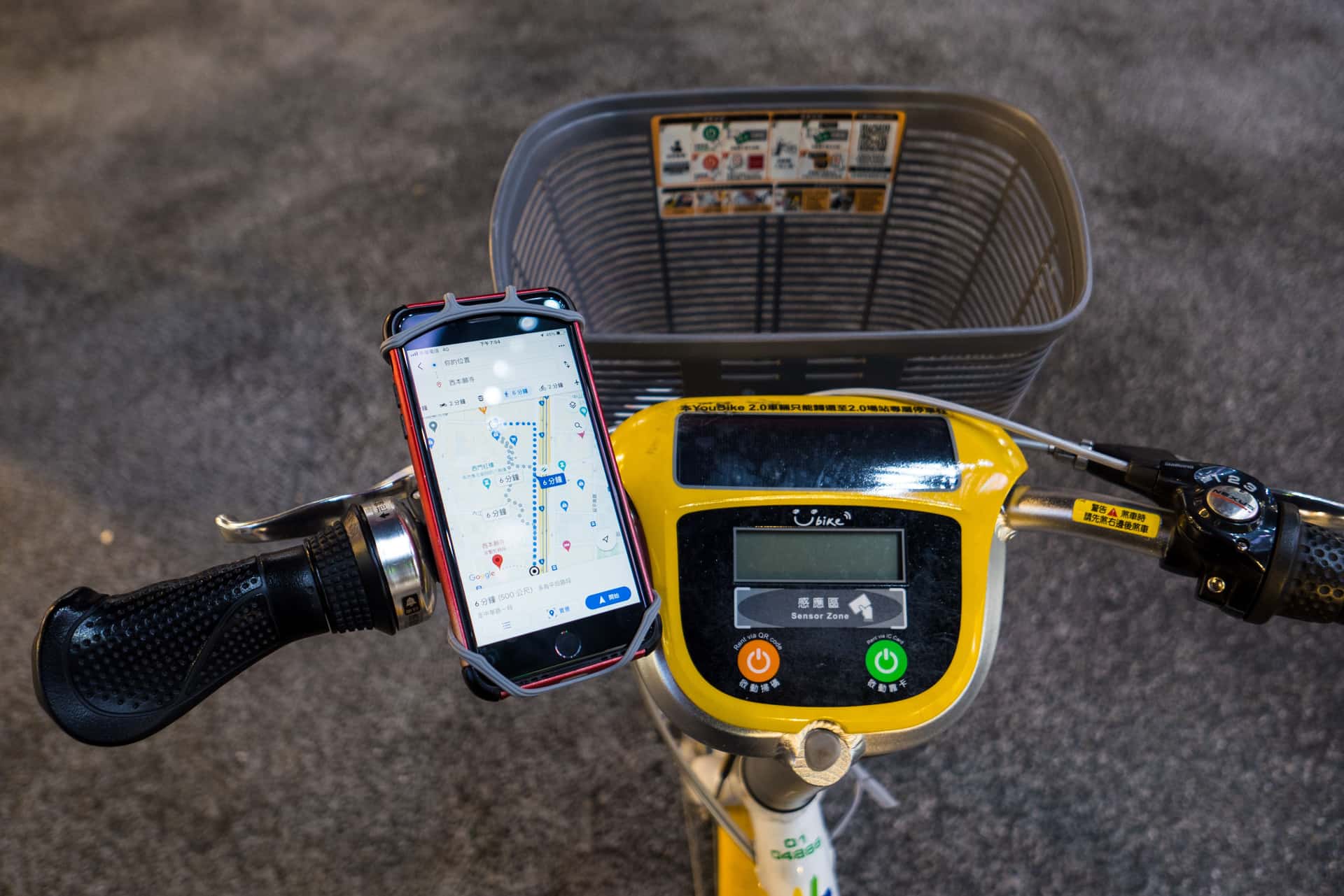 A phone showing a route map mounted on bicycle handlebars
